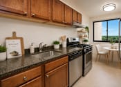 Thumbnail 7 of 18 - A kitchen with wooden cabinets and a black countertop.