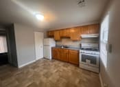 Thumbnail 3 of 3 - A kitchen with wooden cabinets and a tiled floor at Pleasantview Apartments, Baltimore, MD