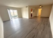 Thumbnail 5 of 10 - LVP  Flooring- an empty living room with wooden floors and a sliding glass door