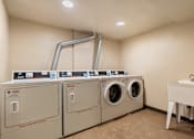 Thumbnail 14 of 23 - A laundry room with washers and dryers and a sink.