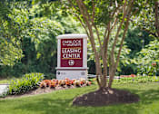 Thumbnail 16 of 23 - A sign for the Overlook Apartments Leasing Center sits in front of a tree.