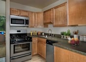 Thumbnail 15 of 29 - A kitchen with wooden cabinets and a black stove top oven at Charlestowne North Apartments, Maryland