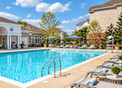 Thumbnail 4 of 29 - A large swimming pool with a white building in the background.