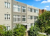 Thumbnail 3 of 14 - a gray building with white windows and trees in front of it