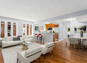 Thumbnail 14 of 14 - a living room with white couches and chairs and a kitchen with a breakfast bar