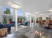 Thumbnail 7 of 15 - community space at Creekside at Taskers Chance in Frederick, MD with blue couches and chairs, and scattered dining tables with four chairs each