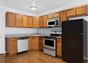 Thumbnail 3 of 6 - a kitchen with wood cabinets and black appliances
