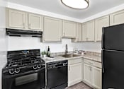 Thumbnail 45 of 46 - A kitchen with black appliances and white cabinets.