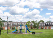 Thumbnail 9 of 10 - A playground with a blue slide and a green slide in the middle of a grassy area at Dutch Village Apartments, Baltimore, Maryland
