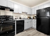 Thumbnail 9 of 46 - A black refrigerator sits in a kitchen with white cabinets at Seven Springs Apartments, College Park
