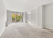 Thumbnail 21 of 41 - A spacious room with a carpeted floor and sliding glass doors leading to a garden.