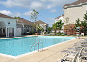 Thumbnail 7 of 17 - a swimming pool with chairs around it in front of a building at Windsor Crossing, Suitland, MD 