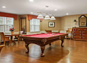 Thumbnail 6 of 29 - A pool table is in the middle of a room with wood floors and wood paneling on the walls.