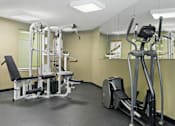 Thumbnail 10 of 29 - A gym with a treadmill, a weight bench and a mirror.