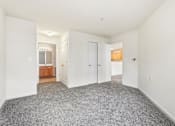 Thumbnail 26 of 29 - A large empty room with a carpeted floor and white walls.