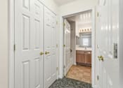 Thumbnail 28 of 29 - A hallway with white doors and a brown cabinet in the middle.