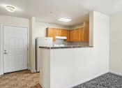 Thumbnail 20 of 29 - A kitchen area with a white door, brown cabinets, and a marble countertop.