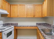 Thumbnail 15 of 29 - A kitchen with wooden cabinets and a white stove top oven.