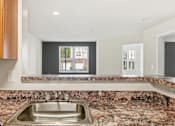 Thumbnail 19 of 29 - A kitchen with a granite countertop and a stainless steel sink.