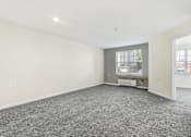 Thumbnail 17 of 29 - A large, empty room with a grey carpet and a window.