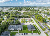 Thumbnail 1 of 17 - A bird's eye view of a residential area with houses, trees, and a parking lot.