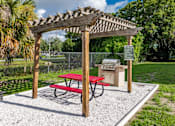 Thumbnail 2 of 17 - A picnic area with a red table and a wooden pergola.