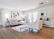 Thumbnail 4 of 17 - A living room with a white couch and a blue rug.