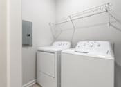 Thumbnail 11 of 20 - Two white front loading washing machines in a laundry room.