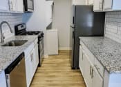 Thumbnail 1 of 13 - an empty kitchen with white cabinets and a black refrigeratorat Retreat at Savannah, Savannah, Georgia