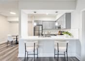 Thumbnail 2 of 20 - A kitchen with white chairs and a white counter.