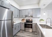Thumbnail 1 of 20 - A modern kitchen with a stainless steel refrigerator and a double oven.