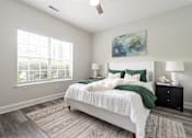 Thumbnail 8 of 20 - A bedroom with a large bed, two lamps, and a painting on the wall.