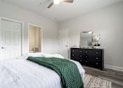 Thumbnail 9 of 20 - A bedroom with a bed, dresser, mirror, and a rug.