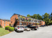 Thumbnail 27 of 29 - a large brick building with a balcony and a parking lot in front of it