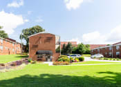 Thumbnail 28 of 29 - a brick building with a black awning in the middle of a grassy area