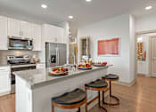 Thumbnail 10 of 44 - A kitchen with white cabinets and a counter with food on it.
