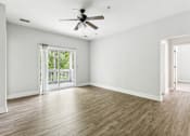 Thumbnail 14 of 18 - A room with a ceiling fan and sliding glass doors leading to a balcony.