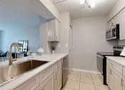 Thumbnail 14 of 17 - A kitchen with a sink, stove, and microwave.