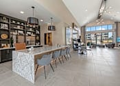 Thumbnail 22 of 44 - A modern kitchen with a marble island and a dining area with chairs.