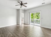 Thumbnail 16 of 18 - A room with a ceiling fan and sliding glass doors leading to a deck.