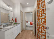 Thumbnail 17 of 44 - A bathroom with a shower curtain that has a pattern of orange and white.