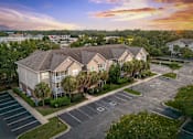 Thumbnail 20 of 20 - A sunset view of a residential area with apartment buildings and a parking lot.