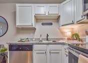 Thumbnail 4 of 14 - a kitchen with white cabinets and a sink and dishwasher