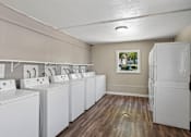 Thumbnail 20 of 22 - A laundry room with a row of washers and dryers.