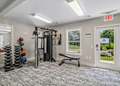 Thumbnail 4 of 22 - A gym room with a bench, weights, and a window.