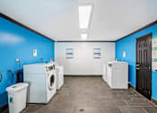 Thumbnail 30 of 37 - A laundromat with a blue wall and a black door.