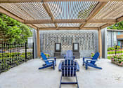Thumbnail 26 of 37 - A patio with blue chairs and a wooden pergola.