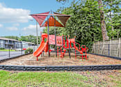 Thumbnail 24 of 37 - A playground with a red slide and a red canopy.