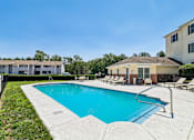 Thumbnail 2 of 22 - A swimming pool surrounded by lounge chairs and buildings.