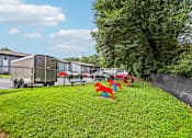 Thumbnail 23 of 37 - A playground with red and blue slides is in the foreground of a grassy area.